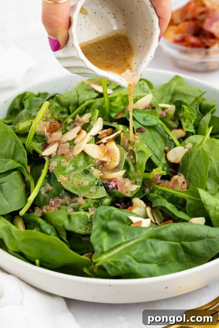 Warm Bacon Vinaigrette 2 Warm hot bacon dressing being generously drizzled over a vibrant spinach salad, making it irresistible.