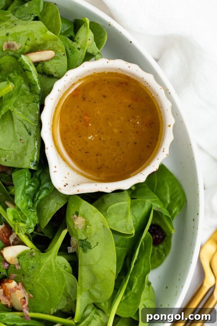 Warm Bacon Vinaigrette 3 Small bowl of hot bacon dressing next to a fresh spinach salad with crumbled bacon and hard-boiled eggs.