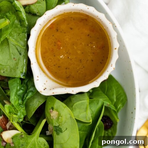 Hot bacon dressing in a small dish next to salad