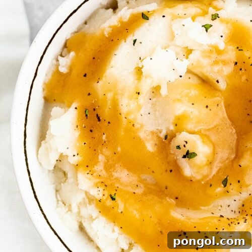 Rich keto gravy poured over creamy mashed potatoes in a bowl, showcasing the perfect texture of this low-carb sauce.