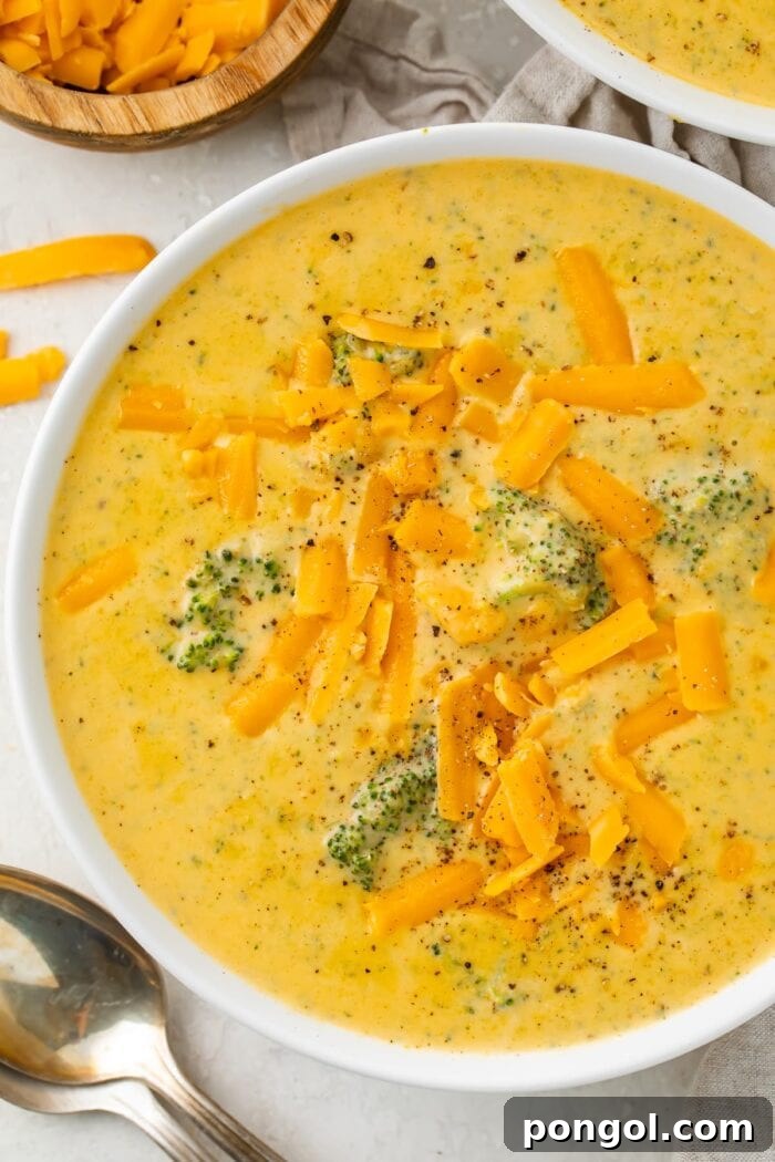 Overhead photo of keto broccoli cheese soup in a white bowl on a white table