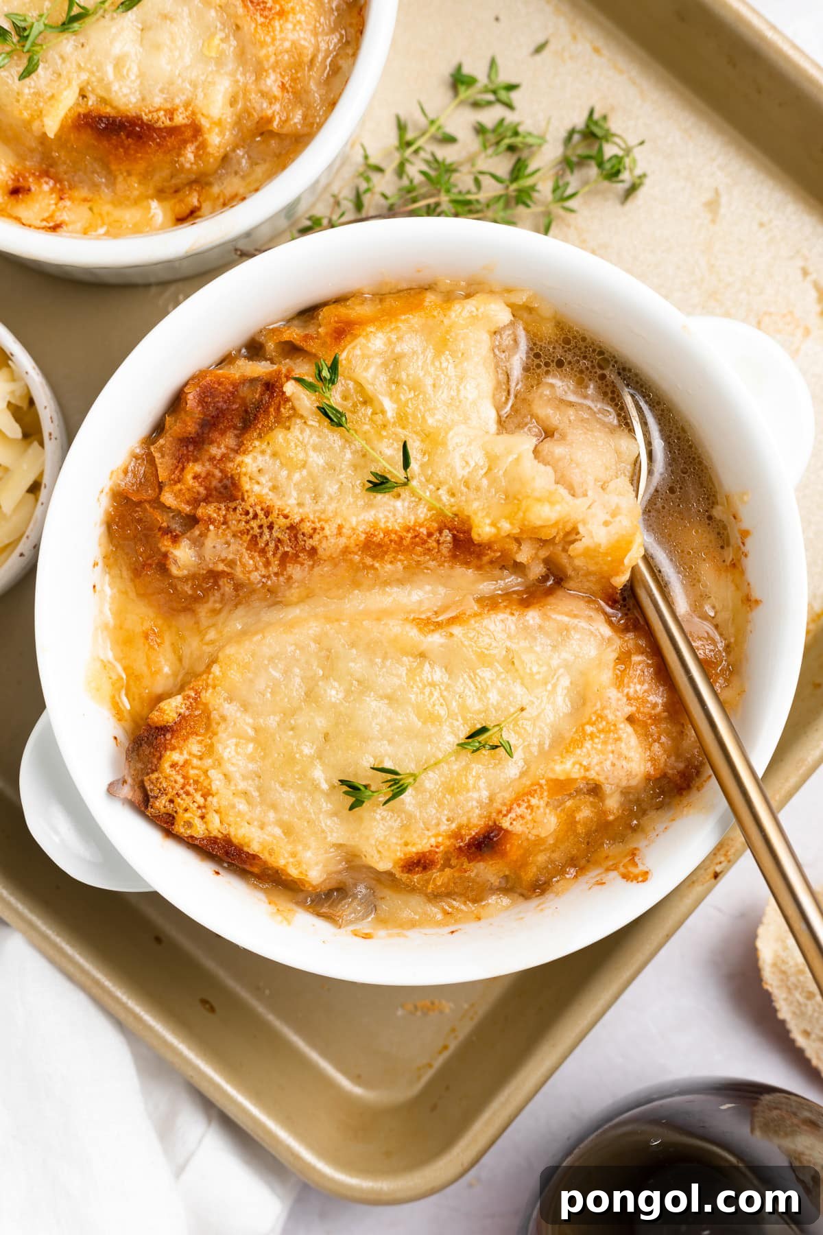 Top-down look at a large ramekin of Instant Pot French Onion soup topped with French bread and melted Gruyère cheese.