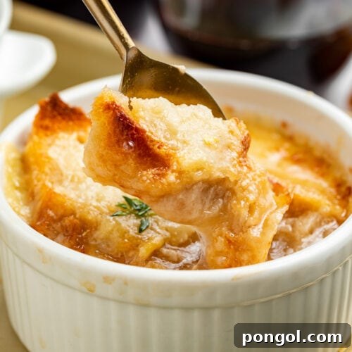 A spoon lifting a piece of French bread off the top of a ramekin holding Instant Pot French onion soup.
