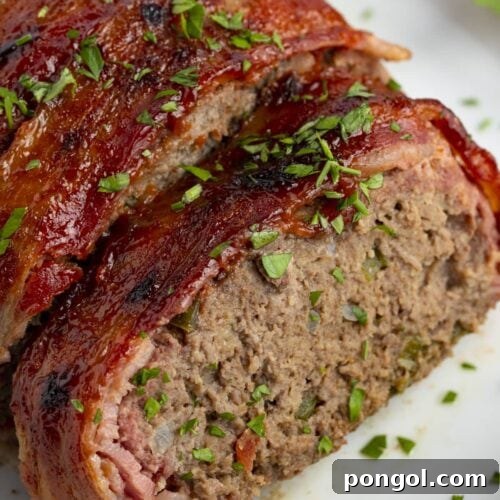 Bacon wrapped meatloaf slices on a white plate with ketchup and garnish