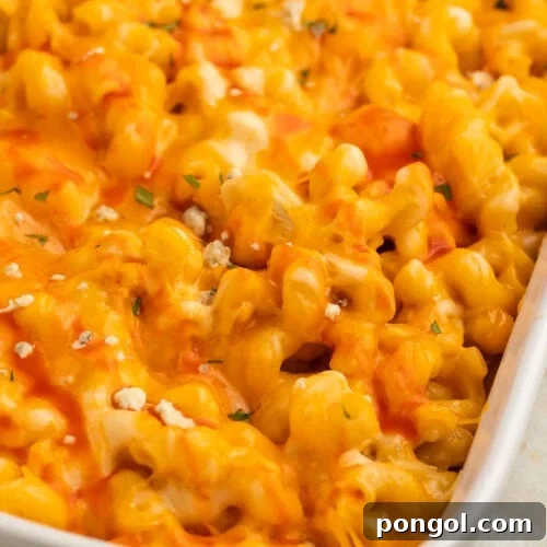 Close-up of orange buffalo chicken mac and cheese in a large rectangular casserole dish.