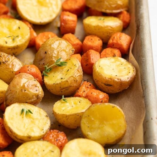 Roasted Potatoes and Carrots on a baking sheet with fresh thyme garnish.