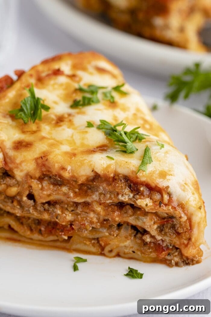 Close up view of a slice of Instant Pot lasagna on a white plate, showing the beautifully cooked layers.