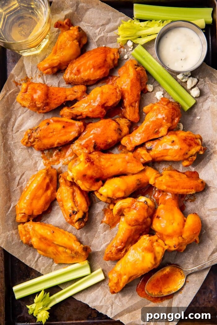 Ultimate Air Fryer Frozen Buffalo Wings 2 Air fryer frozen chicken wings on a baking sheet with parchment paper and celery sticks