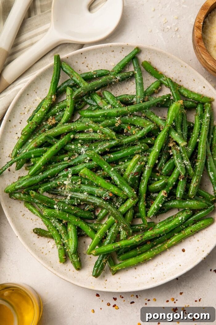 A large plate of vibrant green beans seasoned with Italian herbs