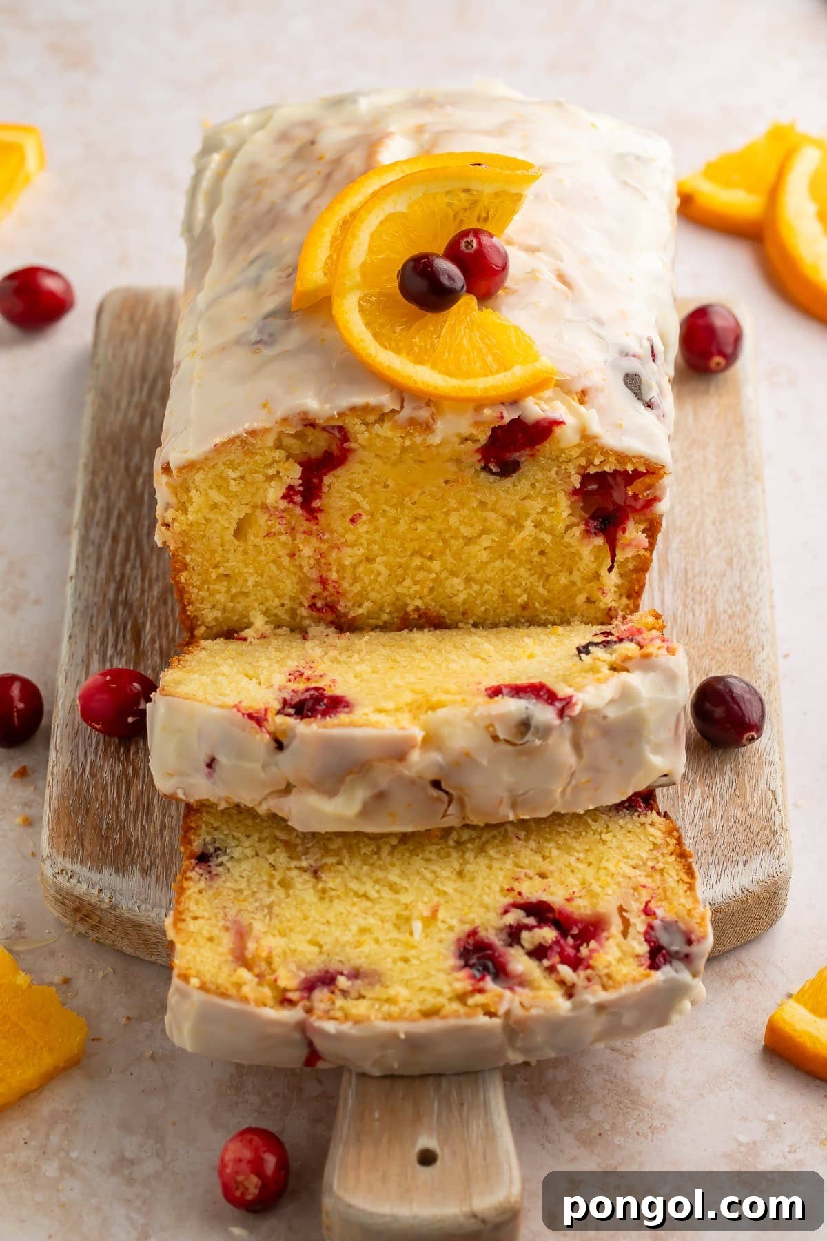 A slice of Cranberry Orange Bread drizzled with orange glaze on a wooden board.