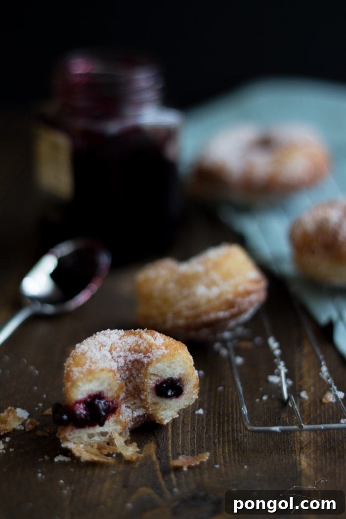 Close-up of a vegan raspberry-filled cronut, showing its flaky layers and sugar coating.