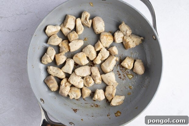 Chicken breast pieces browning in a large skillet