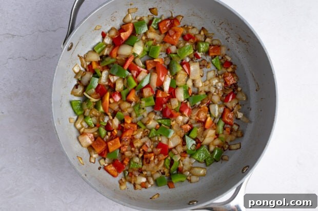 Bell peppers and spices sautéing in a large skillet