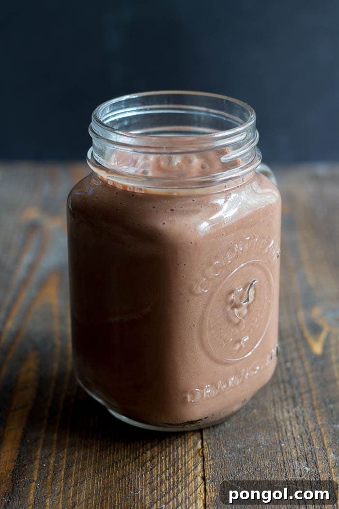 Rich Chocolate Raspberry Maca Smoothie in a glass, garnished with fresh raspberries and chocolate shavings.