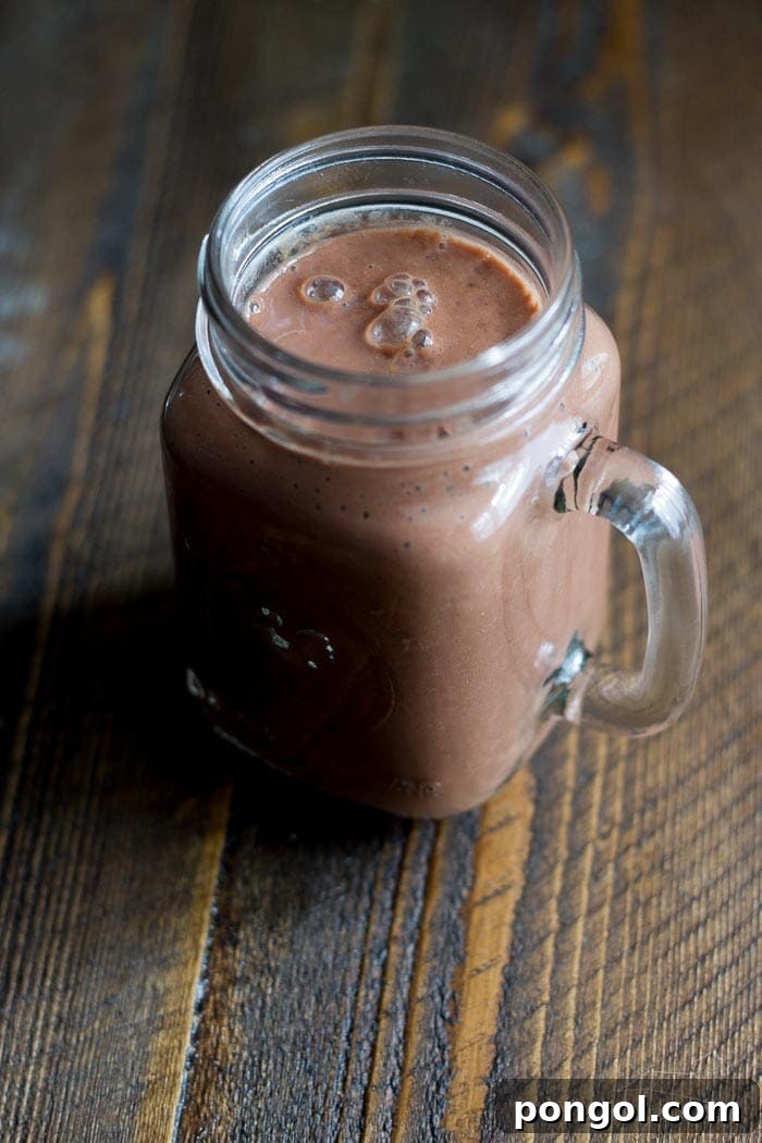 Close-up of a Chocolate Raspberry Maca Smoothie, showcasing its rich texture and topped with berries.