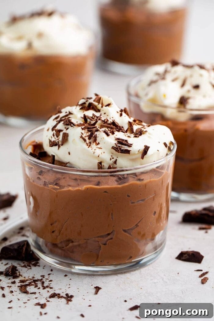 A small glass cup of velvety keto chocolate mousse topped with whipped cream and delicate chocolate shavings.