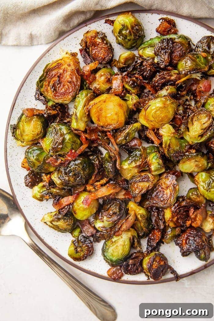 Lifestyle photo of a plate full of crispy oven-roasted Brussels sprouts with bacon.