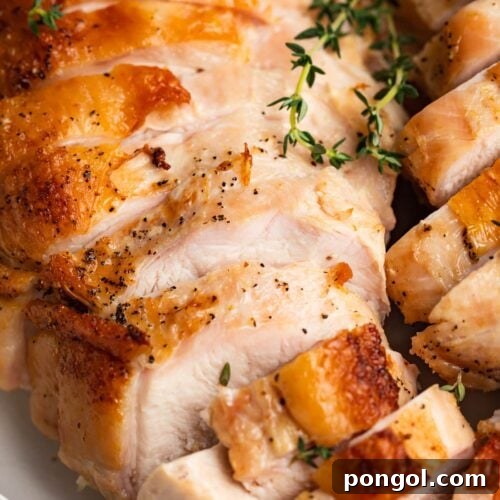 Close-up image of beautifully sliced sous vide turkey breast with fresh thyme on top