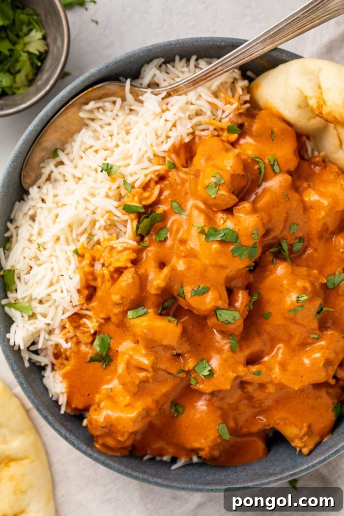 Instant Pot butter chicken, steamed basmati rice, and naan in a large black bowl