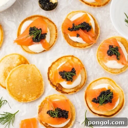 Blini, some topped with salmon and caviar, spread out on a table