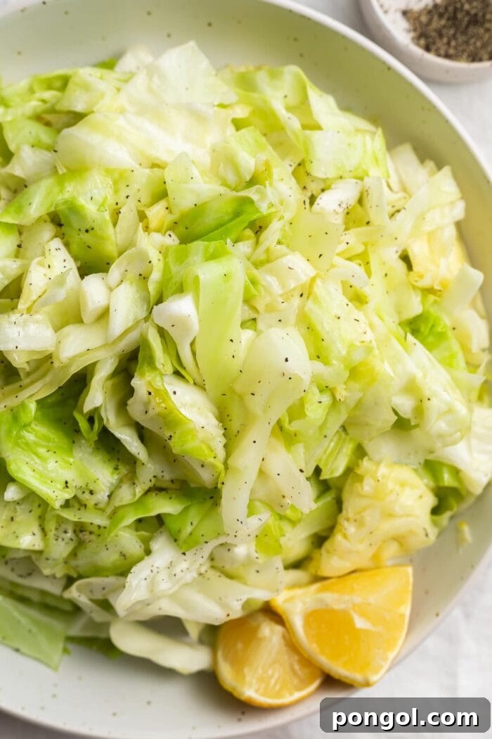 sauteed cabbage in a bowl with fresh lemon sliced and black pepper on the side