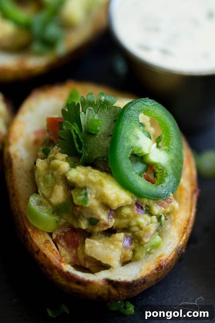 Vegan guacamole potato skins garnished with fresh jalapeño and cilantro.