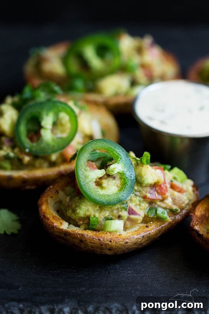 A hand holding a vegan guacamole potato skin, showcasing its appetizing appeal.
