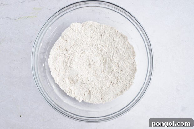 Dry ingredients for sweet potato pancakes in a large glass mixing bowl, perfectly combined.