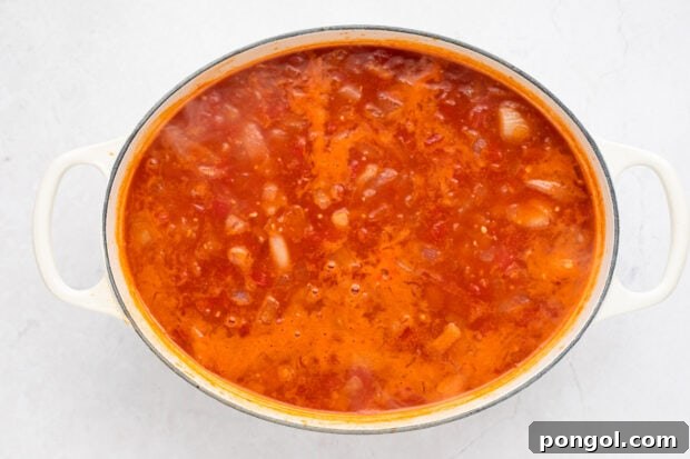 Step-by-step image showing the soup base simmering in a pot with vegetables and tomatoes.