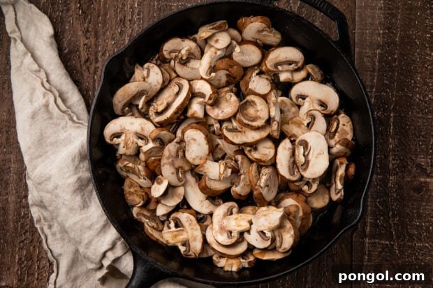 Mushrooms added to a large skillet, ready to sauté.