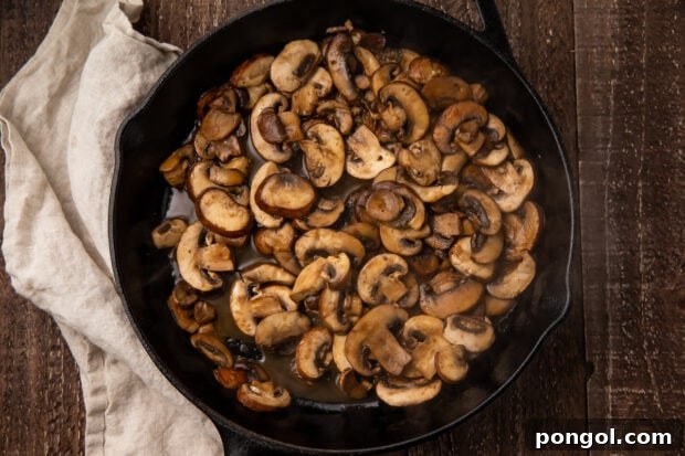 Garlic, Worcestershire, and pepper added to sautéed mushrooms in a skillet.