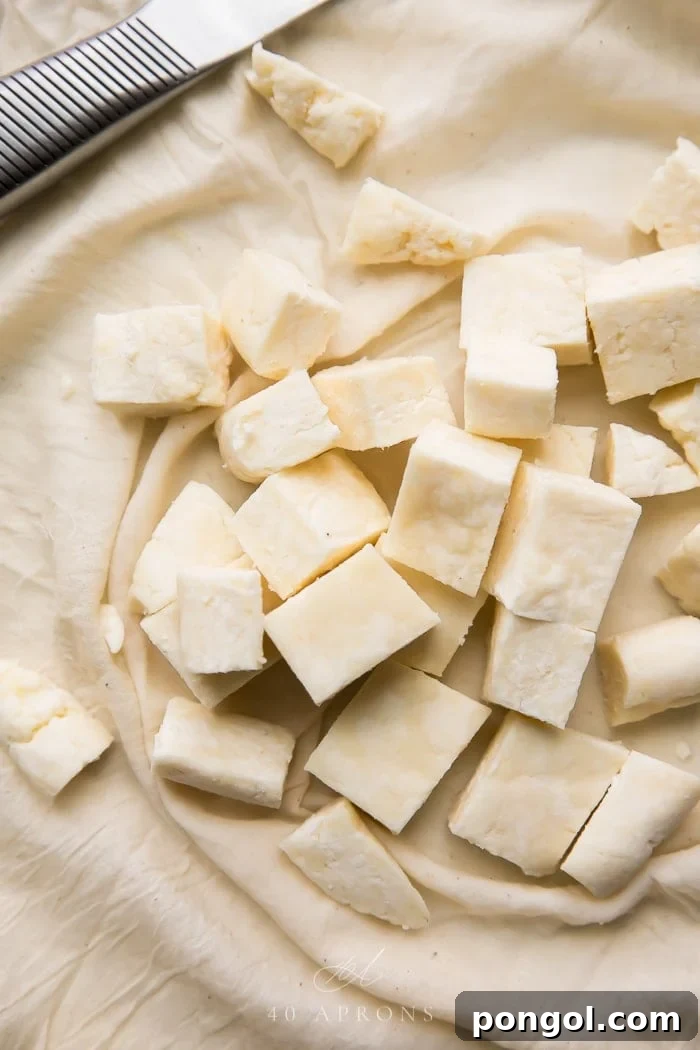 Freshly cut cubes of homemade paneer, the traditional Indian cheese, resting on a clean cheesecloth. The white, firm texture of the paneer is visible, ready to be incorporated into various Indian dishes, highlighting the delicious result of a successful cheese-making process.