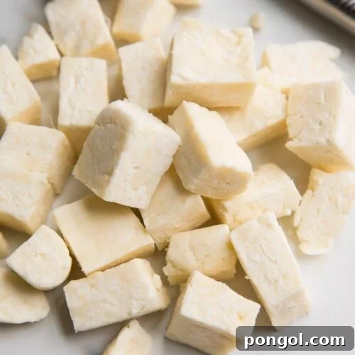 Cubes of fresh homemade paneer, Indian cheese, expertly arranged on a pristine marble surface. The paneer's soft, white texture is inviting, indicating its readiness to be used in a delicious Indian culinary creation. This image emphasizes the quality and simplicity of making paneer at home.