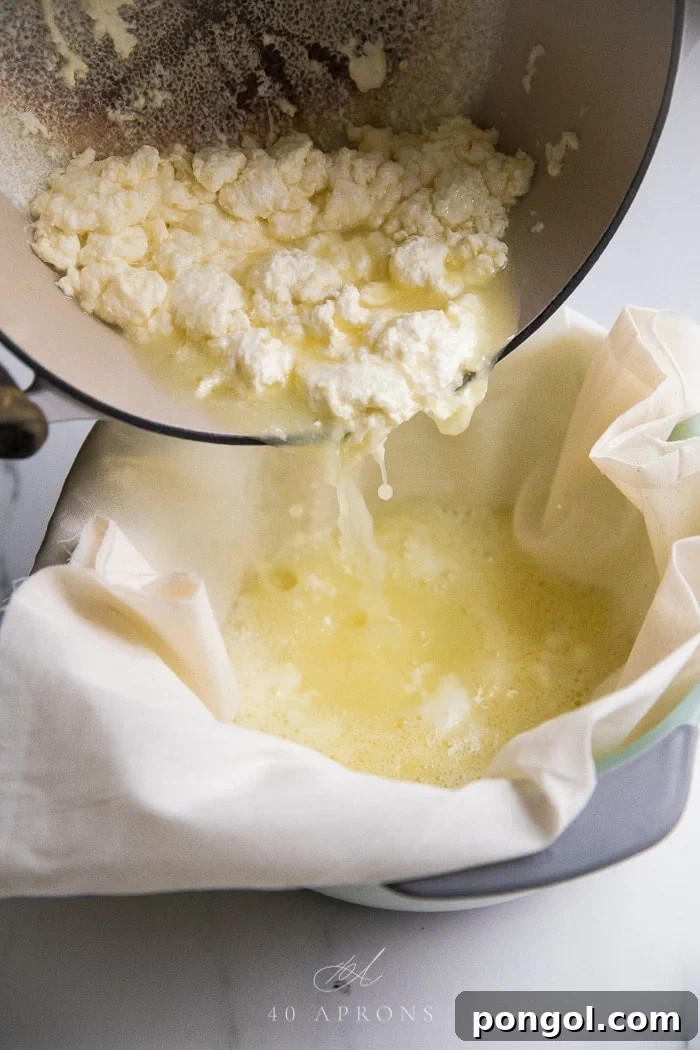 A clear image depicting the process of pouring milk curds into a cheesecloth-lined colander. The curds are visibly separating from the yellow liquid whey, which drains into the bowl below, illustrating a crucial step in making fresh, homemade Indian paneer cheese.