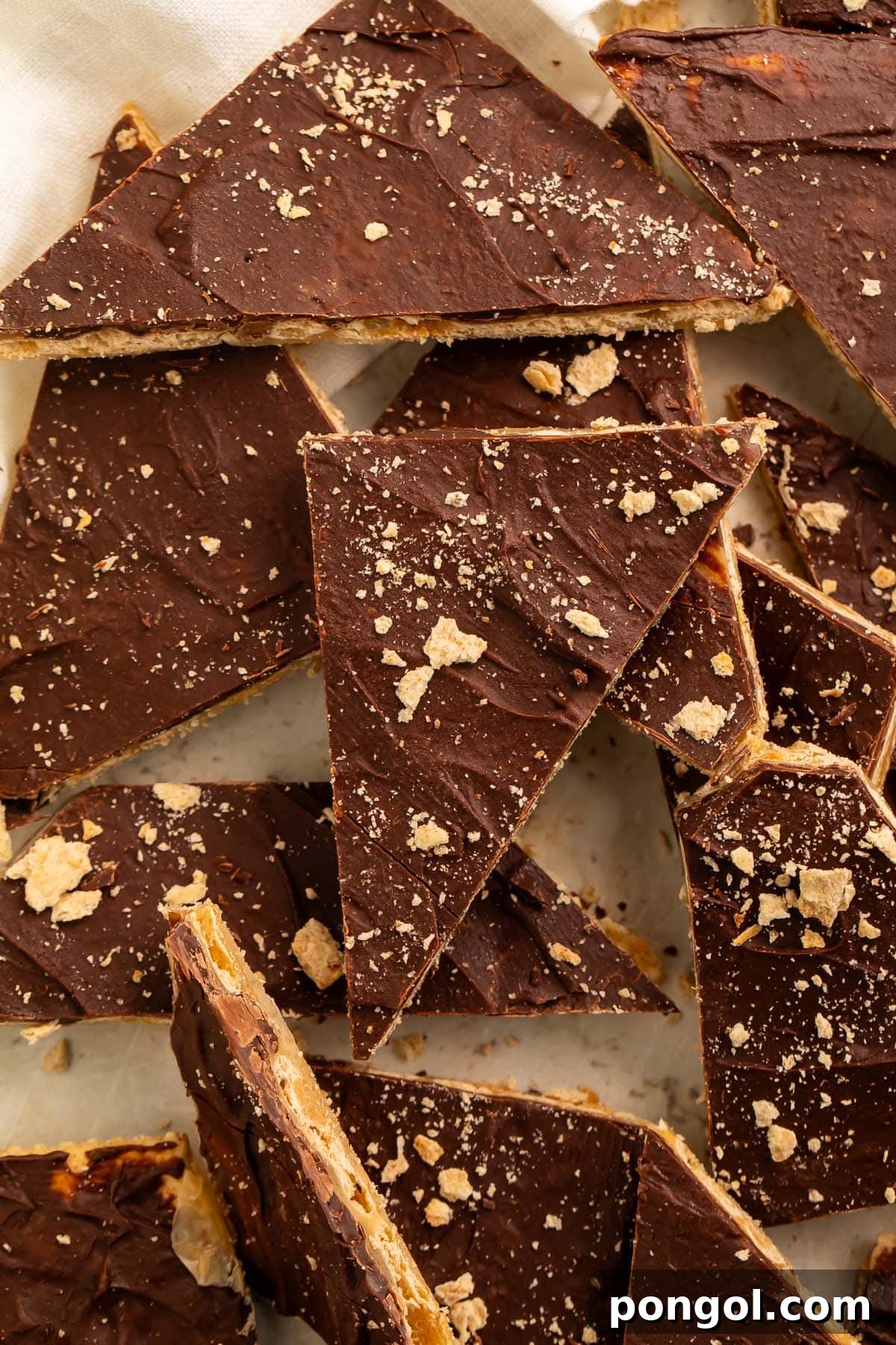 A vibrant close-up of a saltine toffee piece, highlighting the crisp cracker texture and the glistening caramel and chocolate.