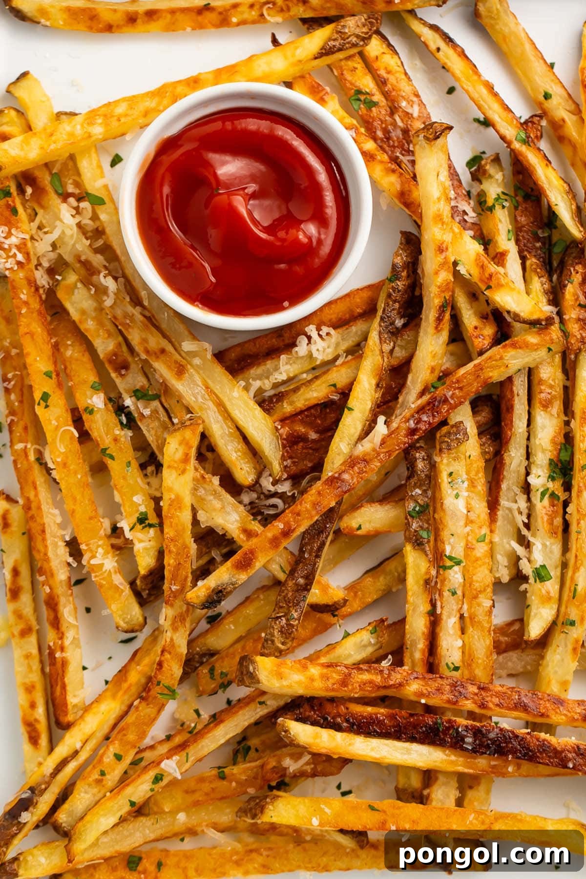 A wider view of the sheet pan filled with golden-brown Parmesan truffle fries, ready to be served, with a small portion of ketchup on the side.