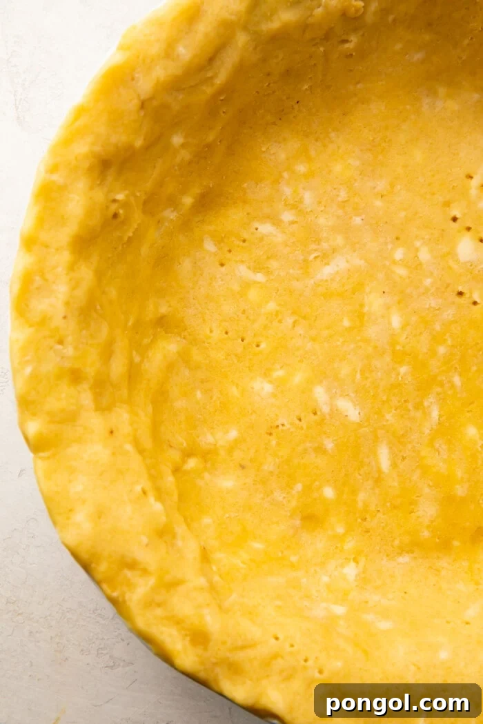 Perfectly Flaky Keto Gluten-Free Low-Carb Pie Crust 3 Overhead view of a keto pie crust in a pie dish, with a fork mark pattern on the base.