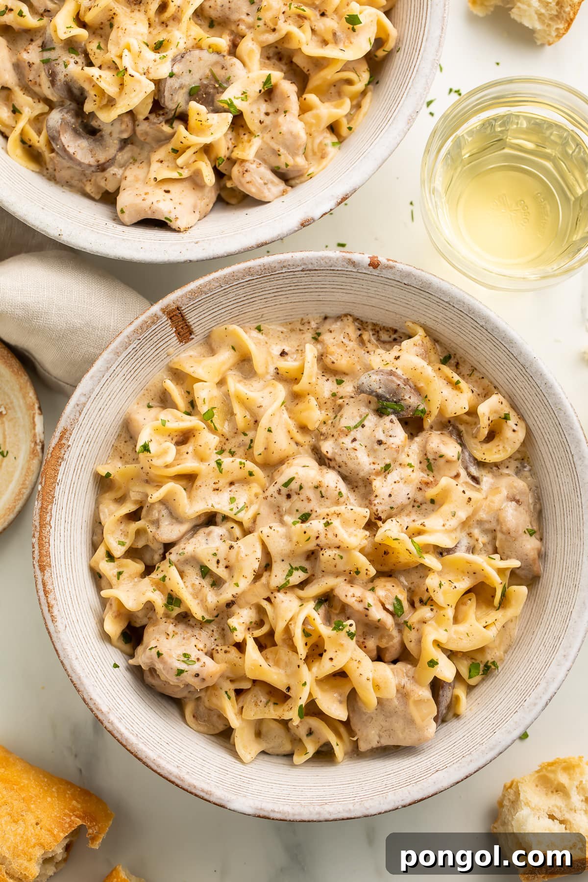 Creamy Chicken Stroganoff 3 Chicken stroganoff plated in a large round bowl on a neutral table next to a cloth napkin, ready to be served.