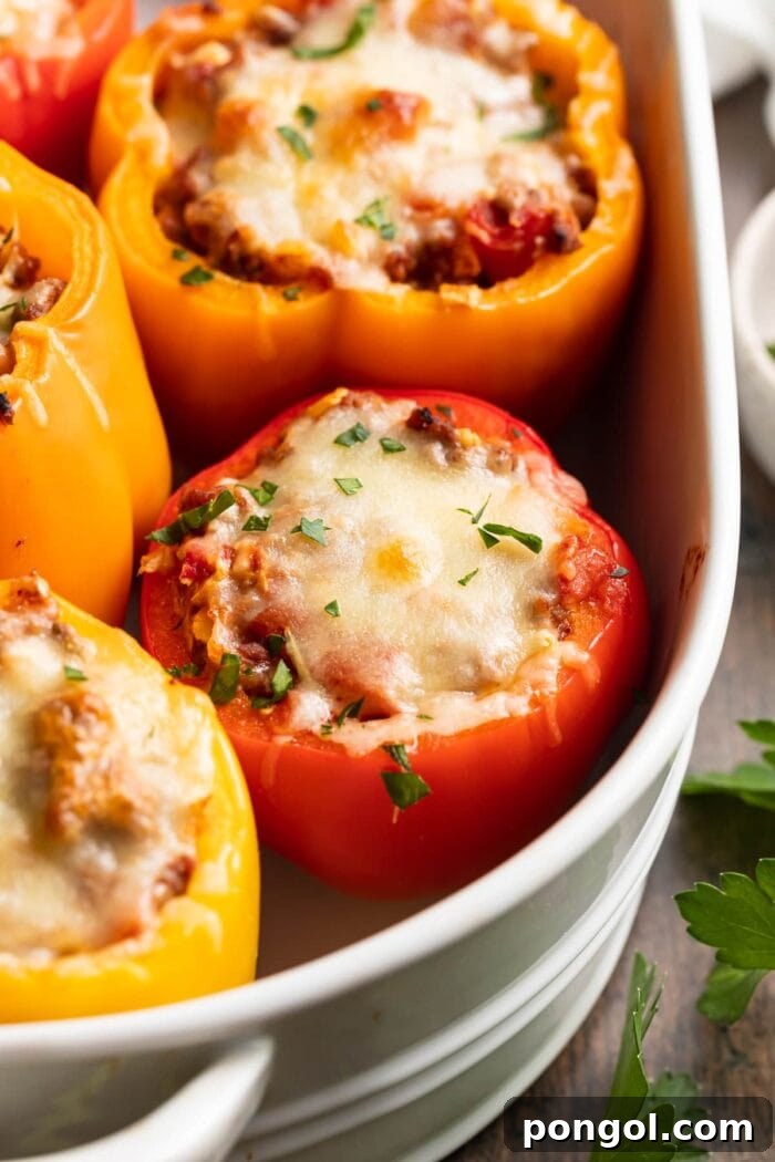Low Carb Stuffed Peppers 3 keto stuffed peppers in a baking dish with fresh parsley