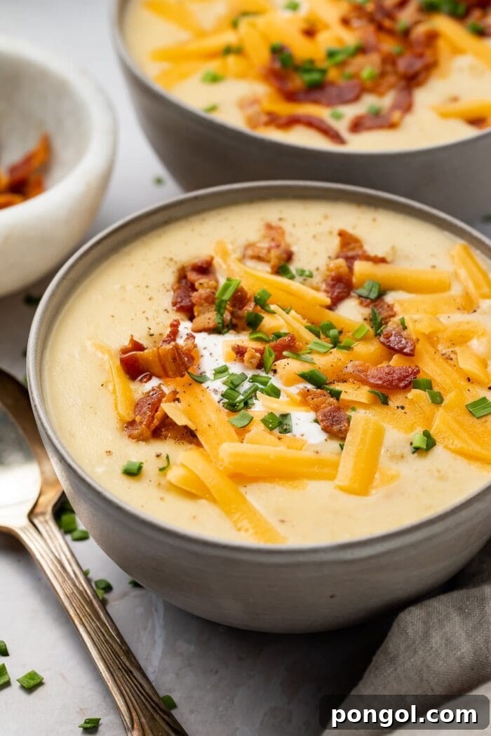 Instant Pot potato soup in black soup bowls, garnished with fresh herbs and crumbled bacon