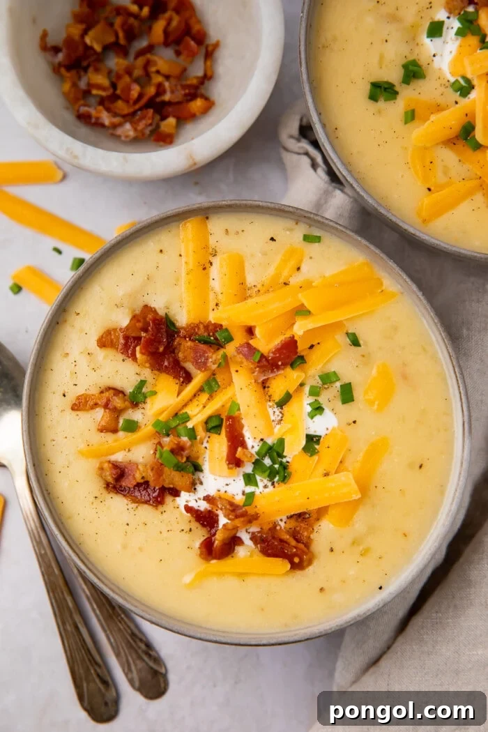 Overhead view of Instant Pot potato soup in black soup bowls, garnished with crumbled bacon and chives