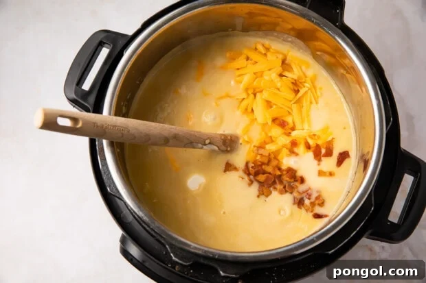 Instant Pot potato soup with shredded cheese and bacon stirred in