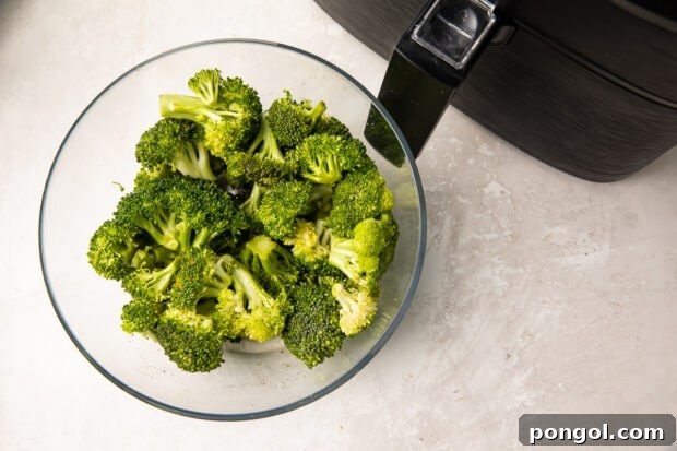 Broccoli in a glass bowl next to an air fryer