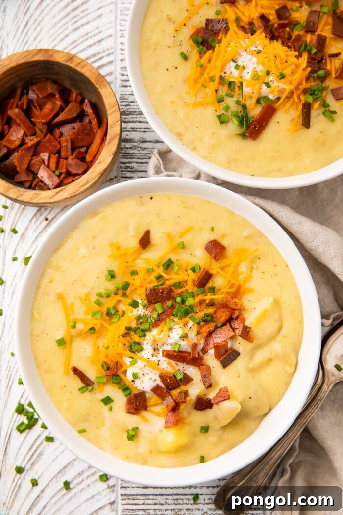 Overhead view of two bowls of vegan potato soup on a table, beautifully presented with various toppings.