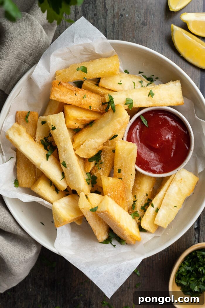 overhead image of yucca fries on a plate with ketchup and fresh parsley on the side