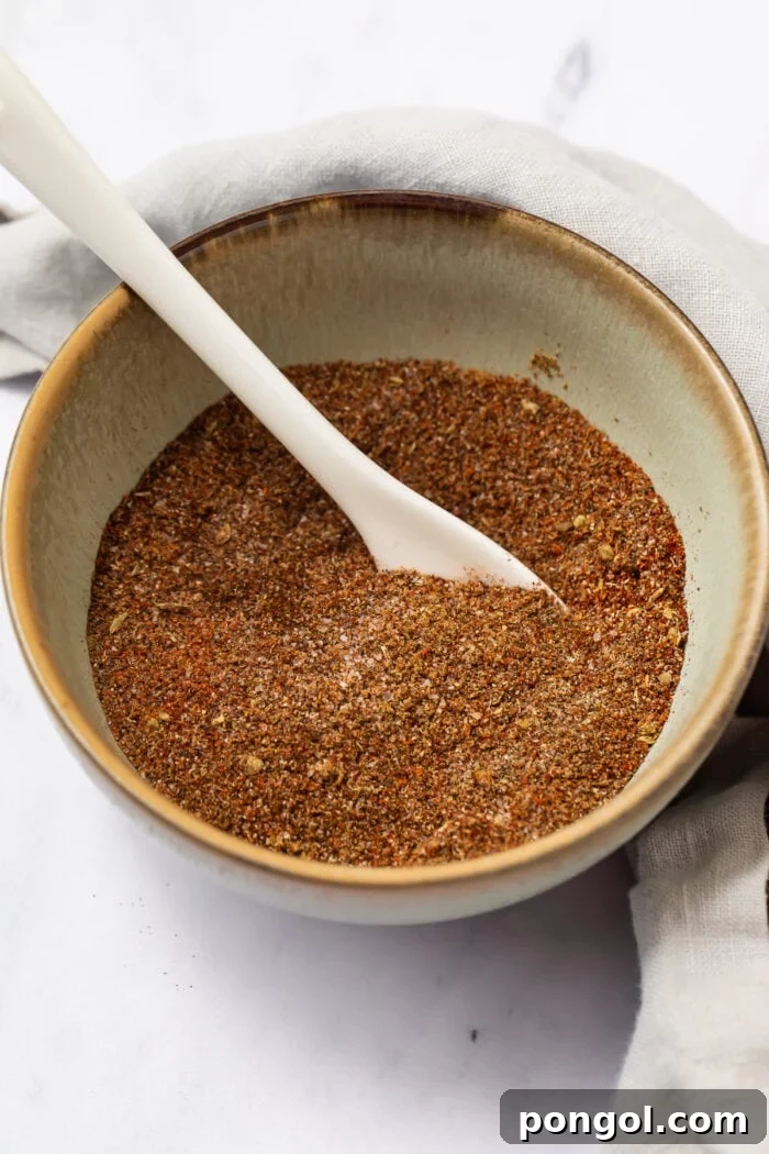 Keto taco seasoning in a bowl with a white spoon, showcasing a vibrant blend of spices