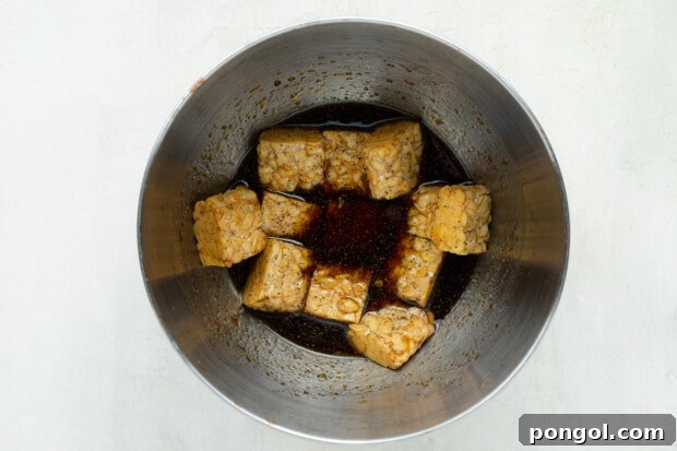Tempeh cubes soaking in marinade in a bowl