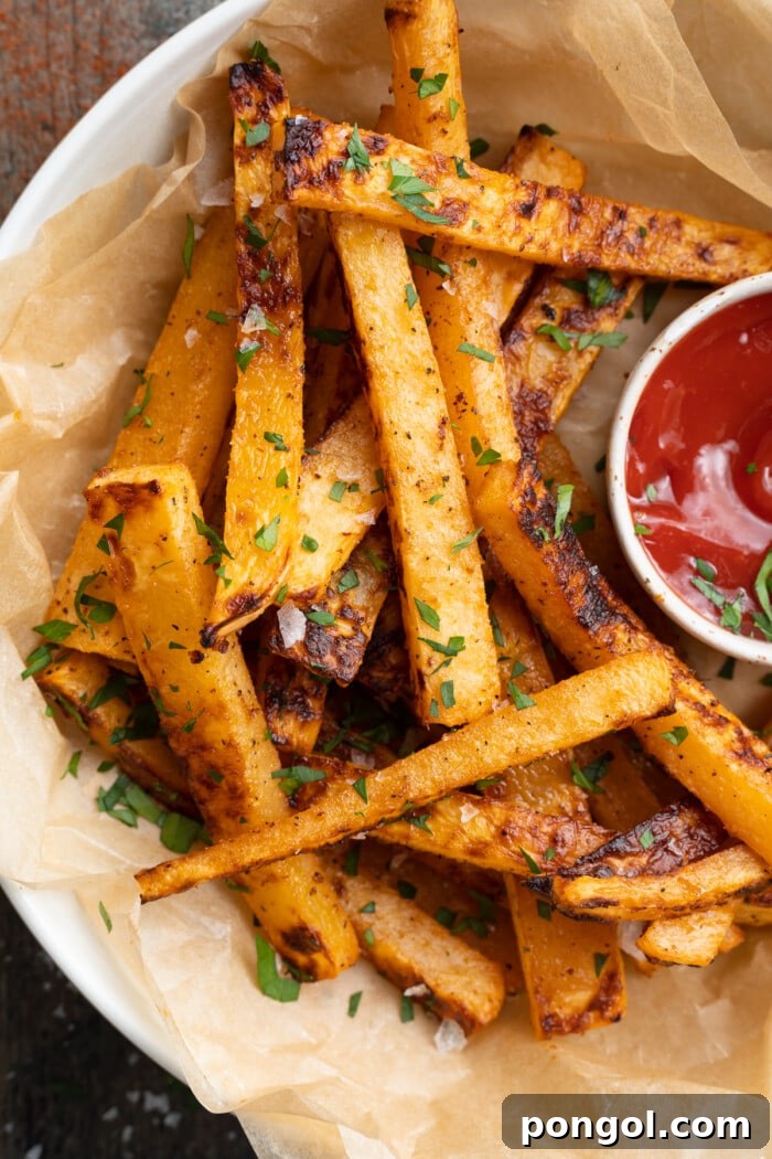 Overhead shot of freshly baked rutabaga fries in a white bowl with a side of ketchup