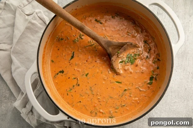 Cashew cream being stirred into the lasagna soup in a large pot