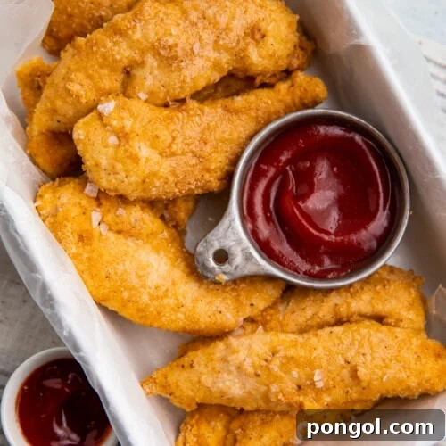 Whole30 chicken tenders in a baking dish with a compliant dipping sauce